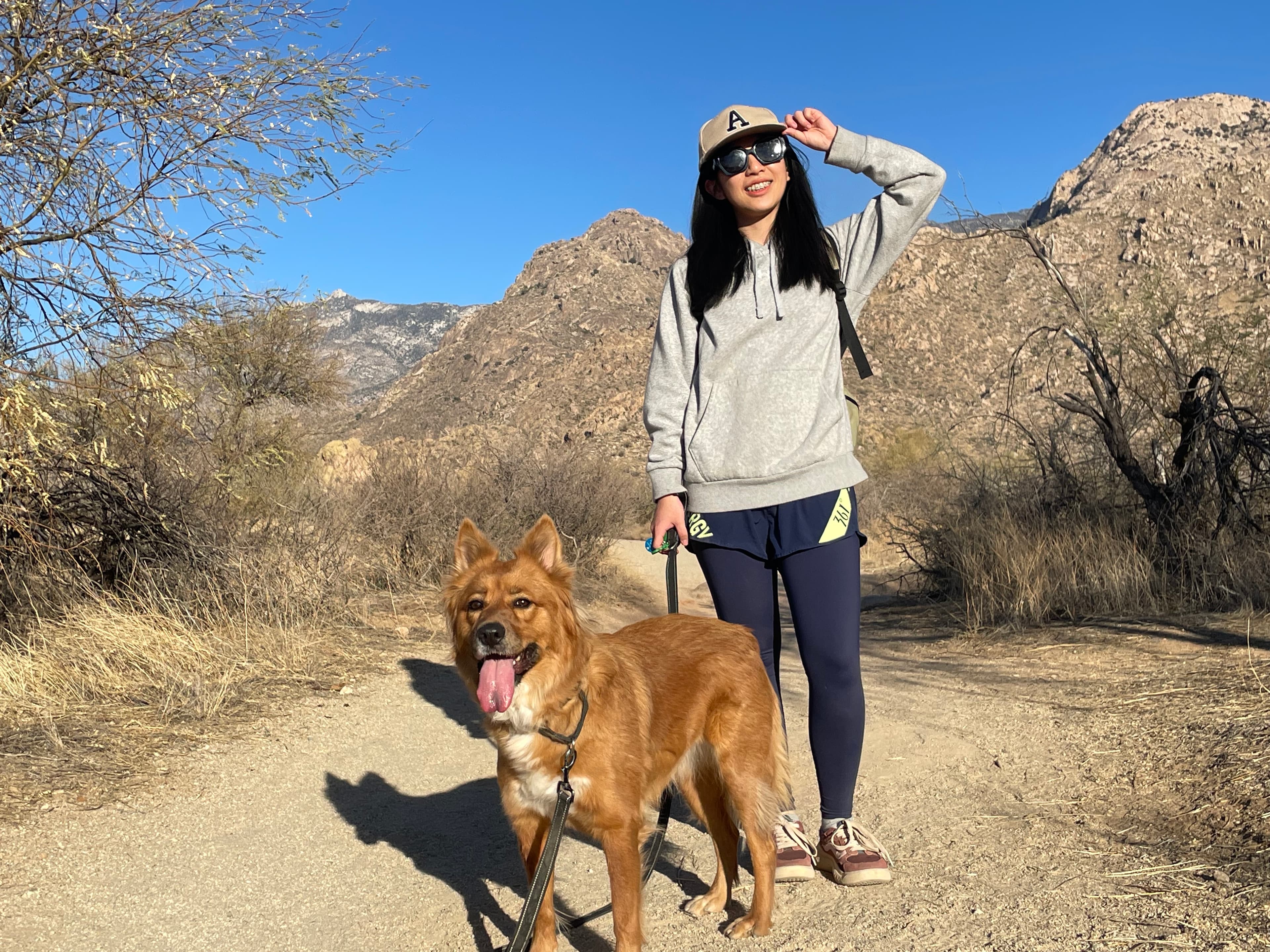 Yuxin Lin outdoors in Arizona with her dog Miso on a hiking trail.